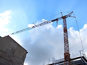 A construction crane rises into a blue, slightly cloudy, sky